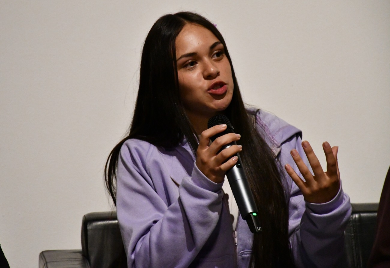 Niña con expresión seria y micrófono en mano, participando activamente en el conversatorio.